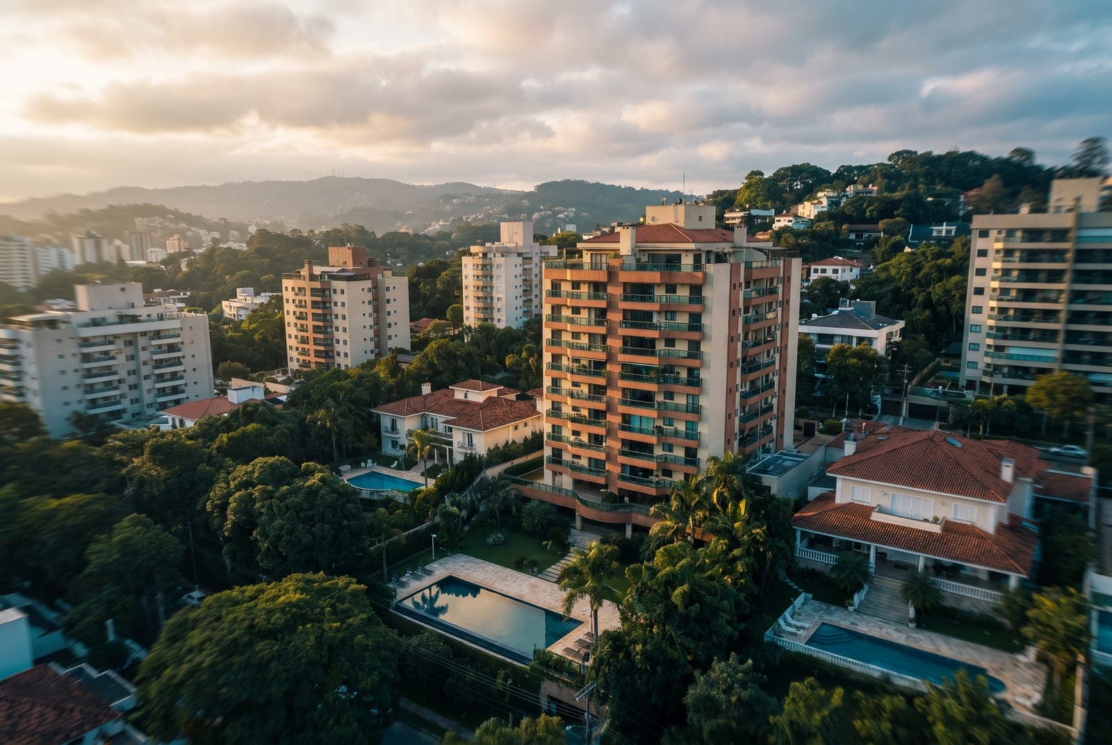 Vista aérea ao entardecer de um bairro residencial arborizado, com um imóvel em destaque sob luz dourada